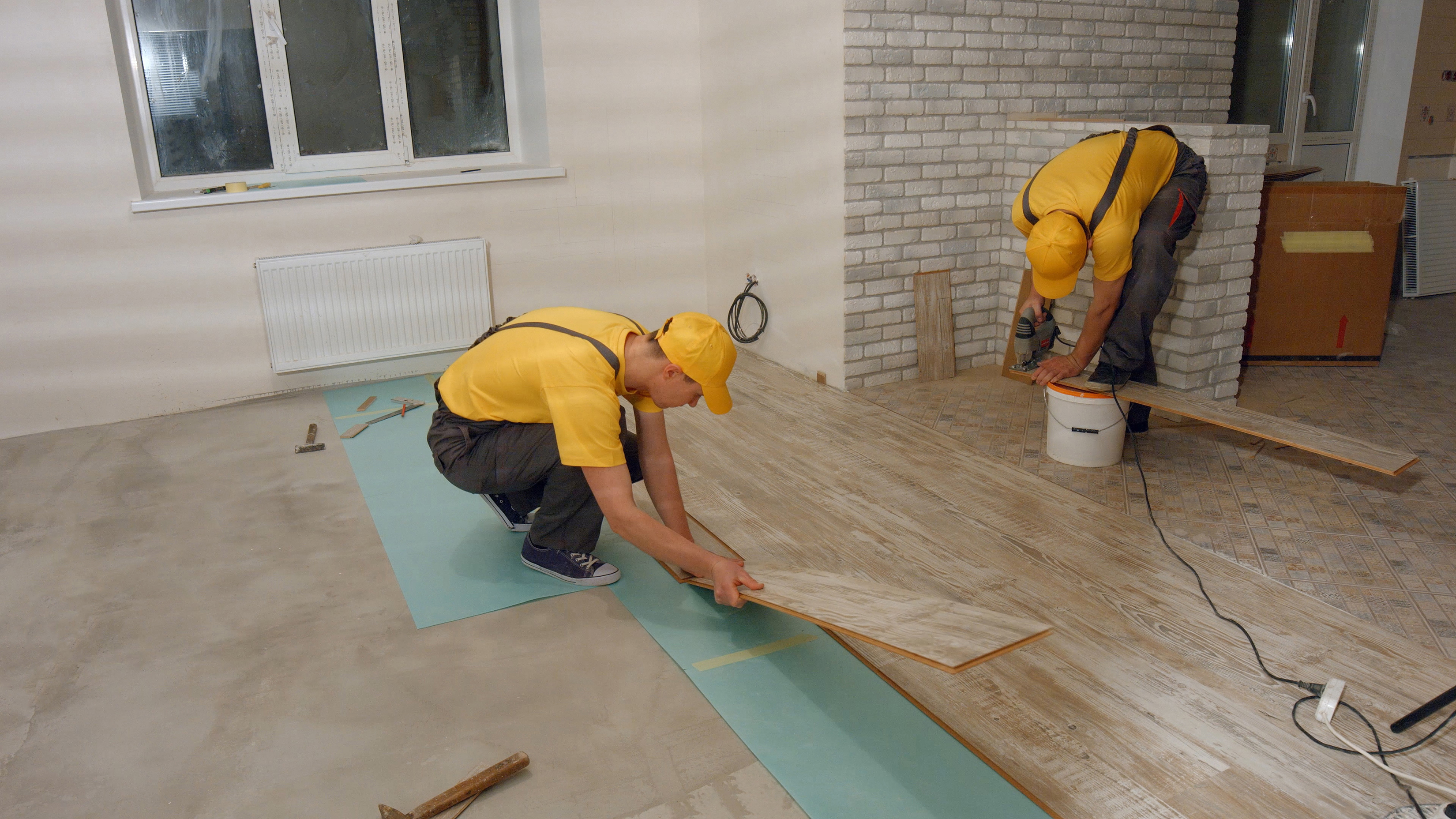 workers installing laminate flooring in a house